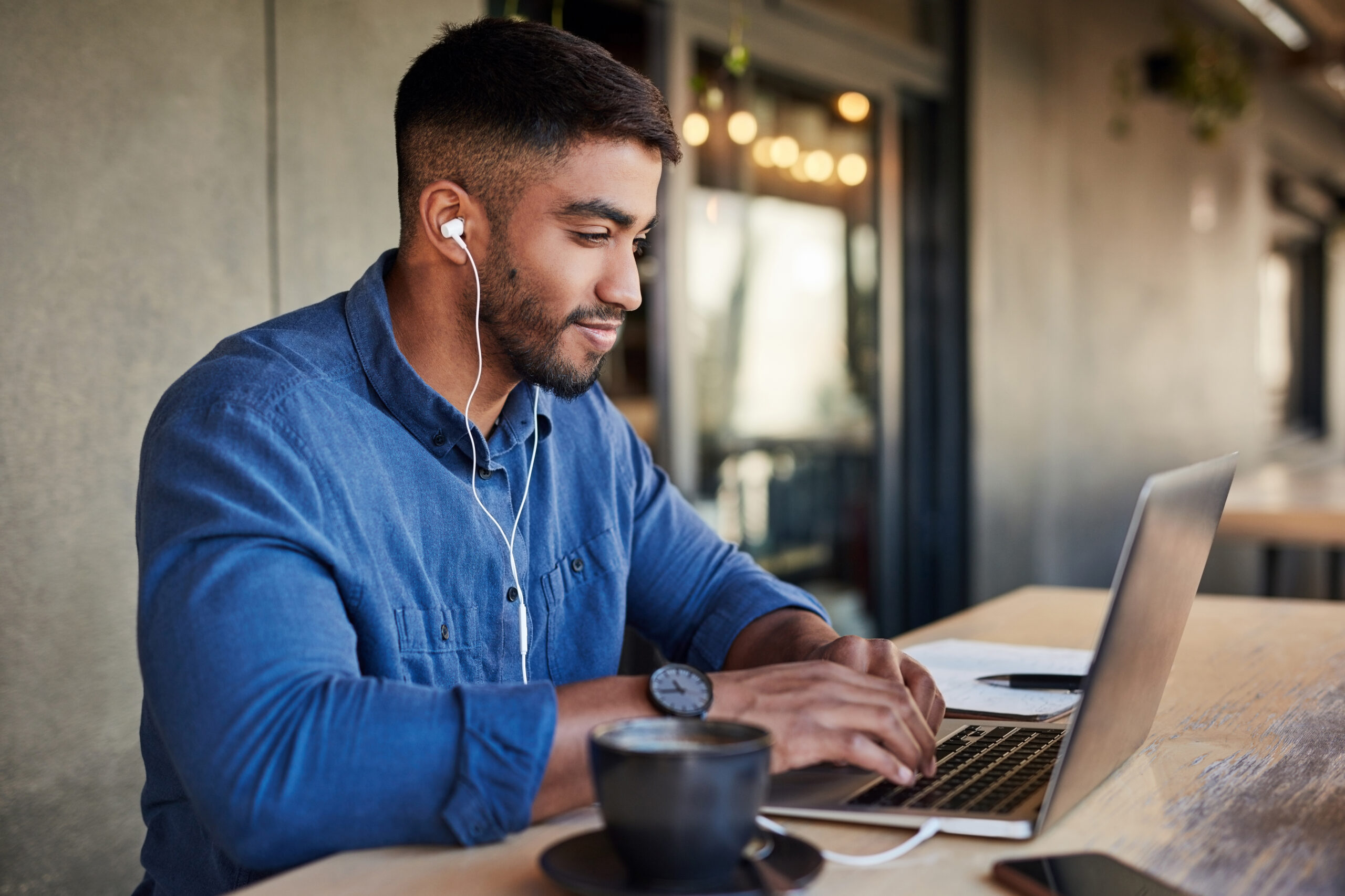 Male real estate agent, earphones or laptop typing in cafe or restaurant